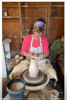 Lori Watts sitting at the potters wheel making a pitcher